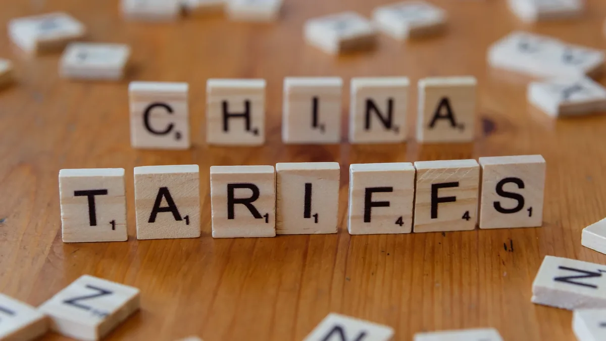 A collection of Scrabble tiles arranged on a wooden surface, spelling out the words "CHINA TARIFFS".