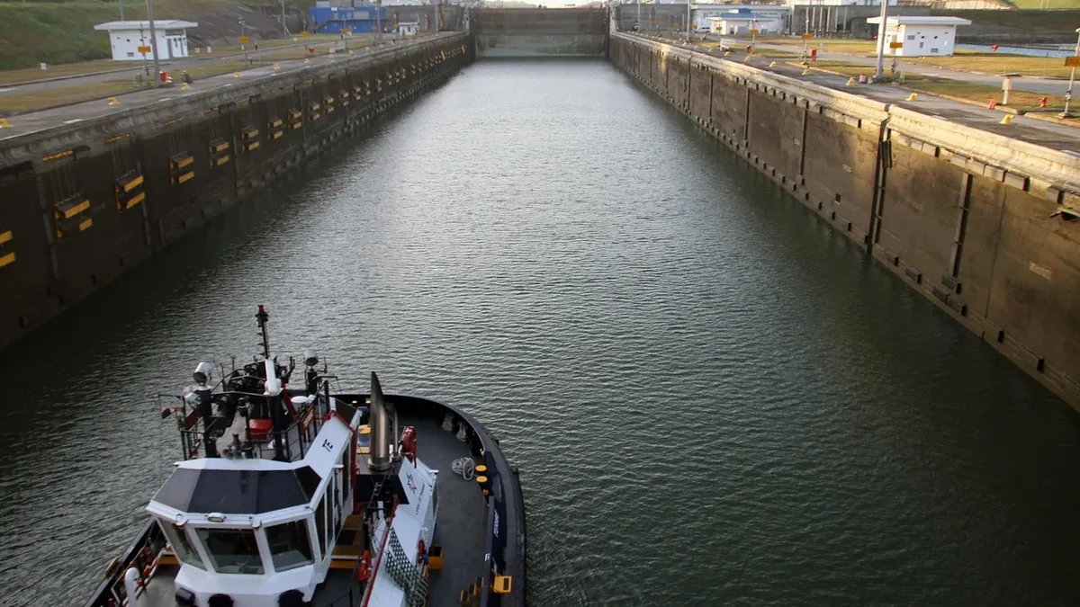 A large boat navigating through a canal with concrete walls on either side.