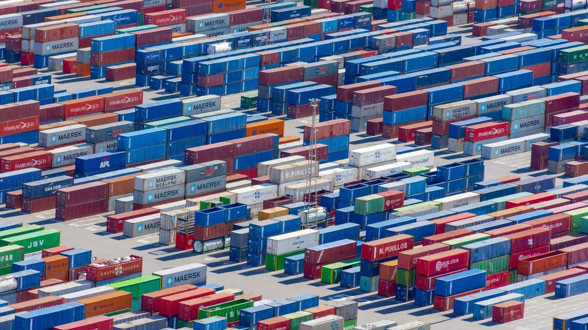 A large number of shipping containers stacked in rows, with some containers stacked on top of each other and others placed side by side.